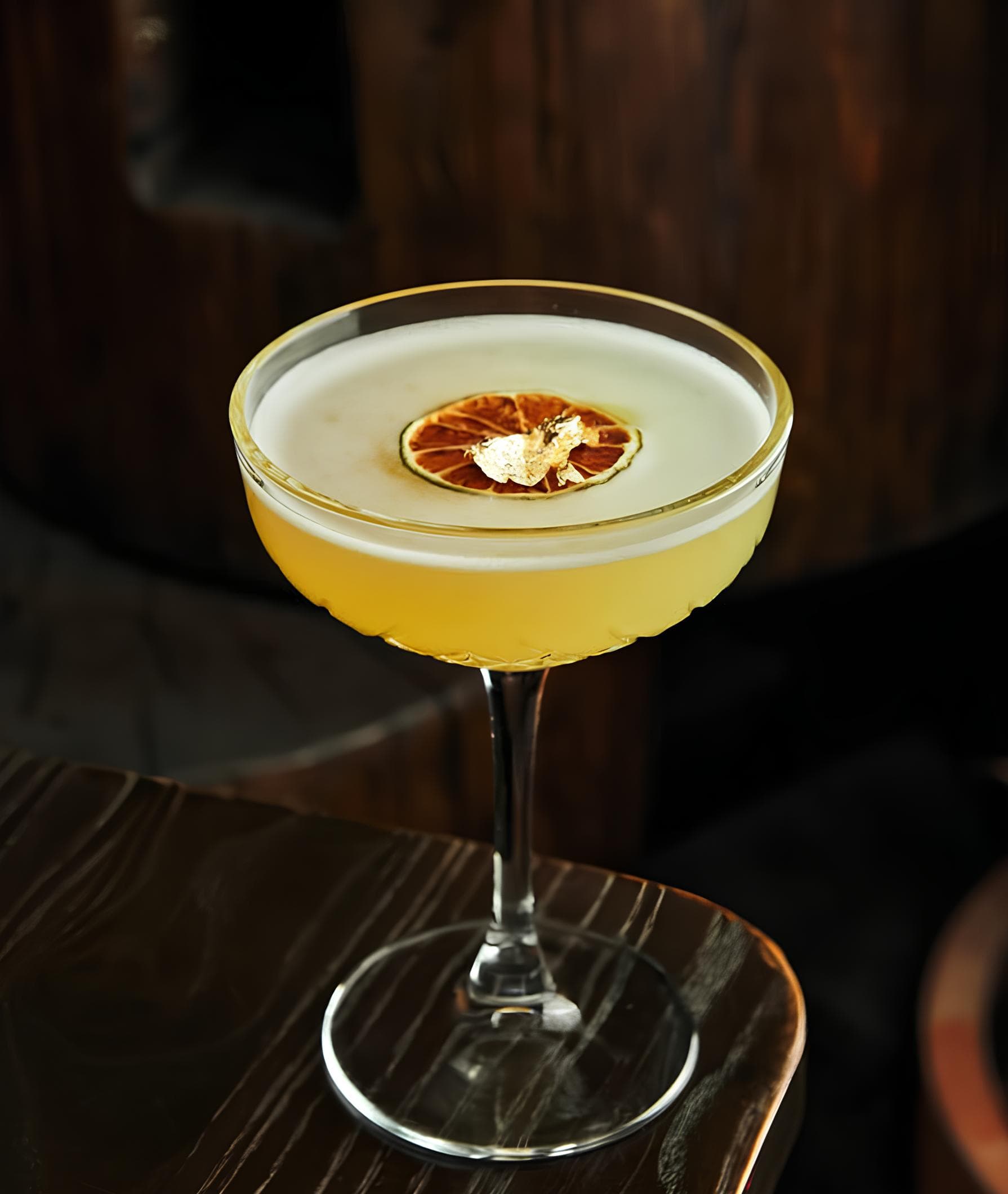 Cóctel cítrico dorado con naranja deshidratada en el bar premium de Puerto Banús